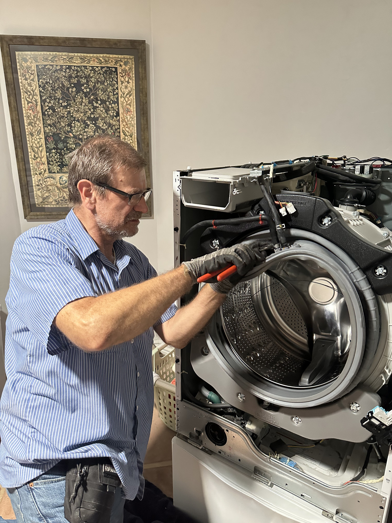 Vladimir repairing a washing machine in a customer's home